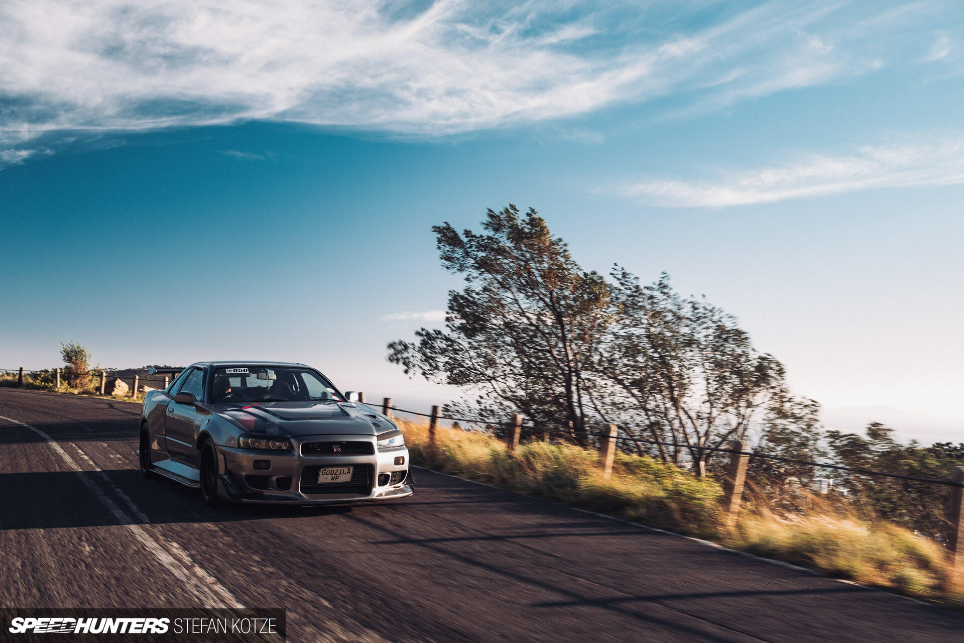 Nissan Skyline R34 GT-R on a mountain road in 
                    a sky landscape