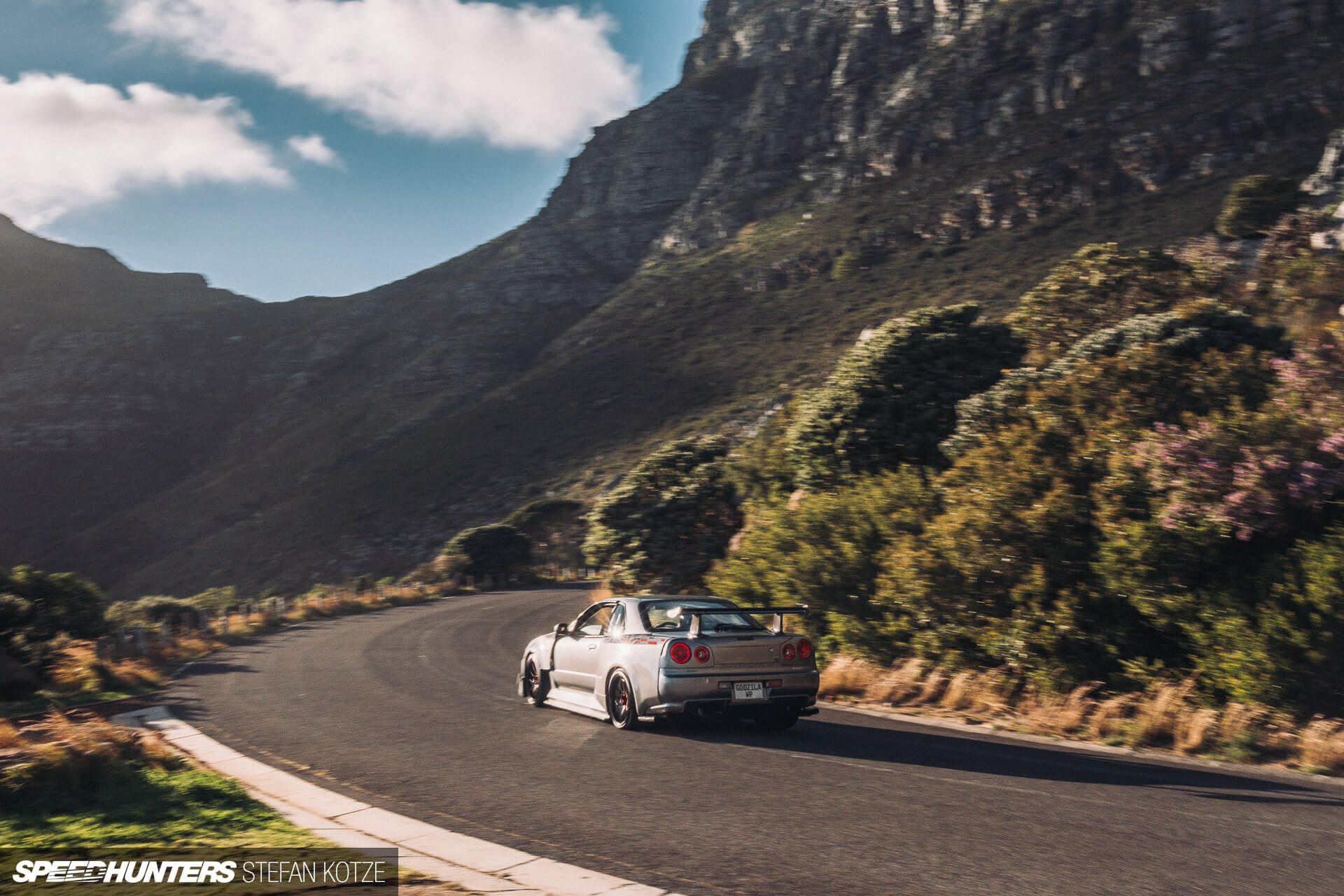 Nissan Skyline R34 GT-R on a mountain road 
                    with a sky background