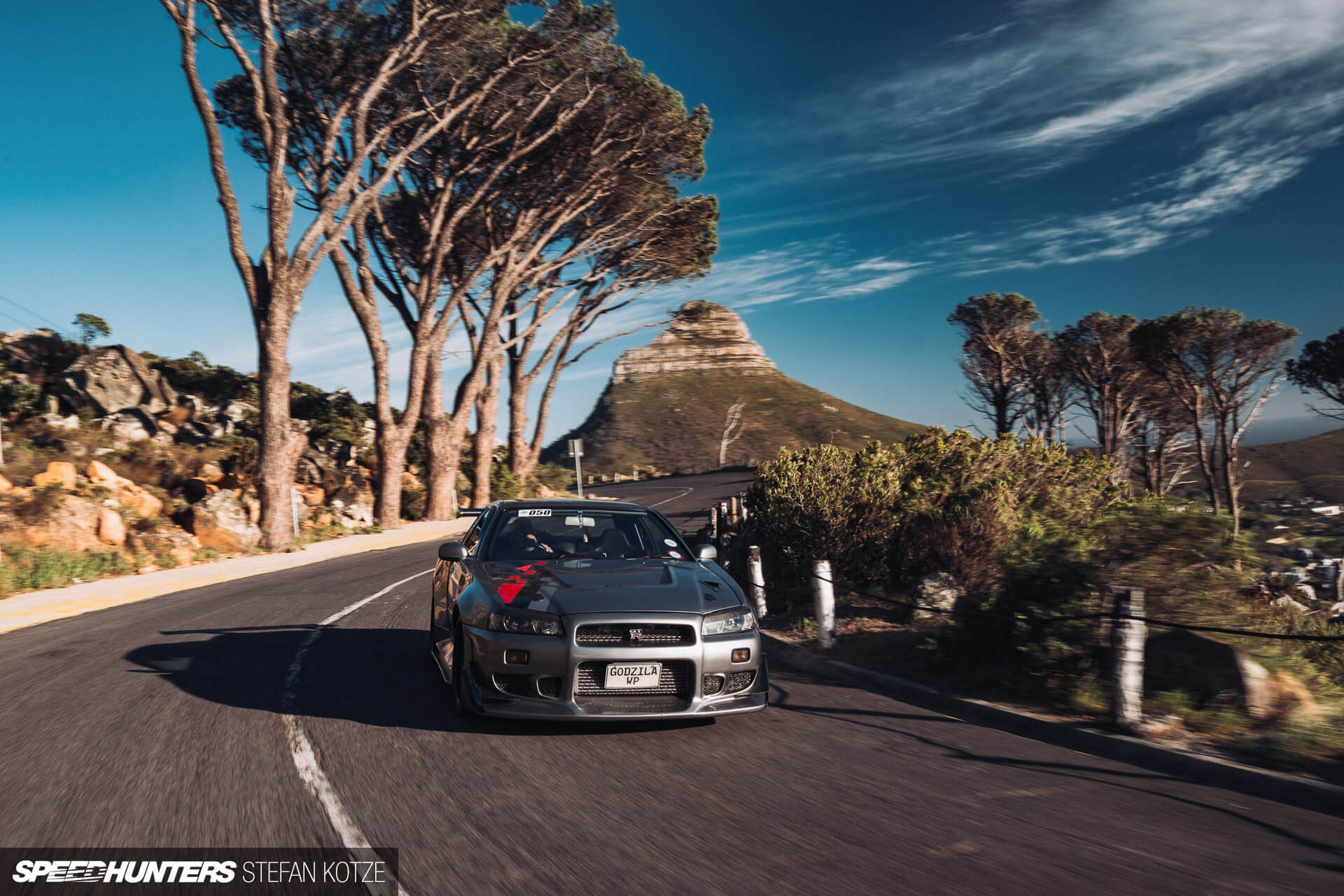 Nissan Skyline R34 GT-R on a mountain road 
                    with a sky background