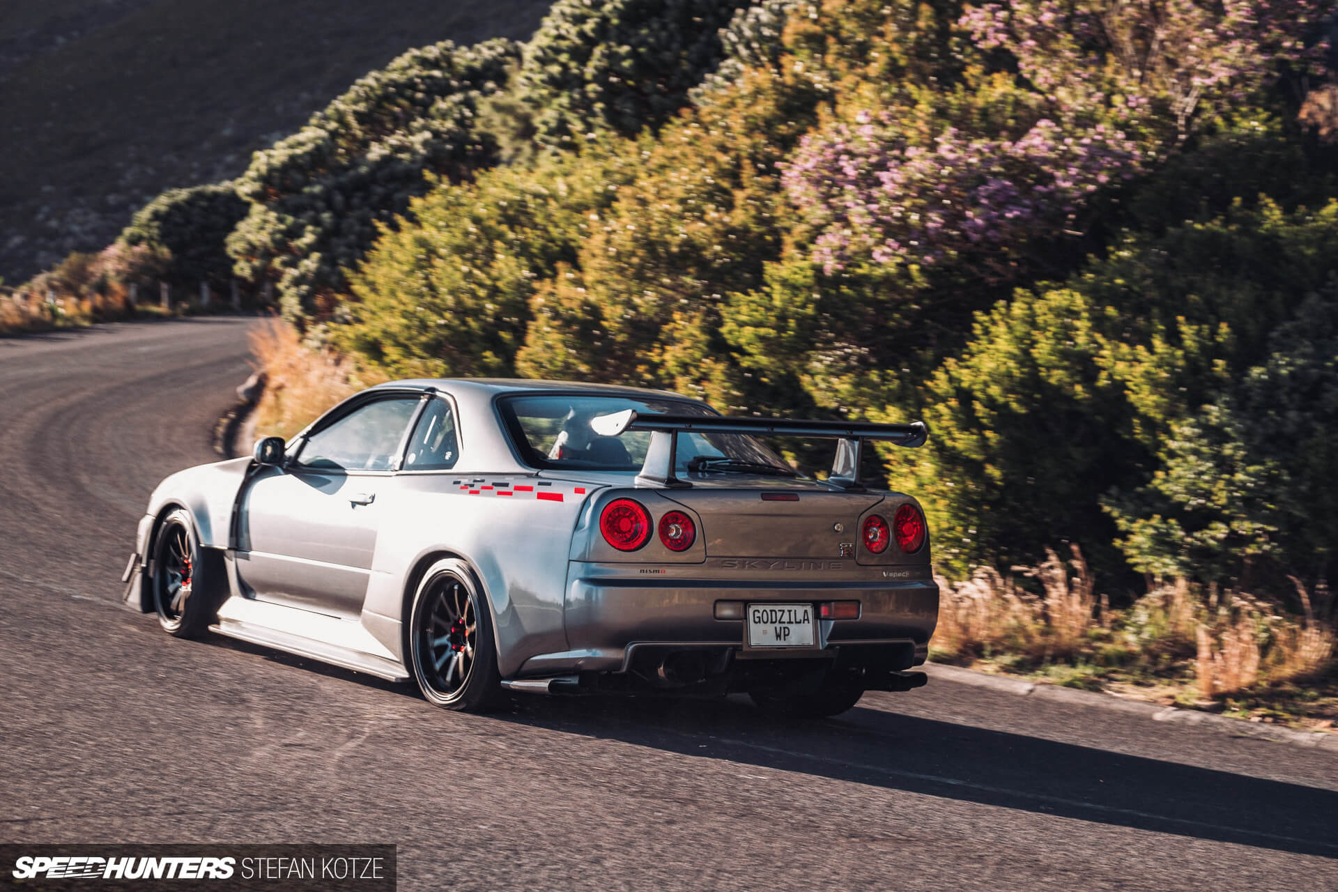 Rear view of the Nissan Skyline R34 GT-R on a 
                    mountain road