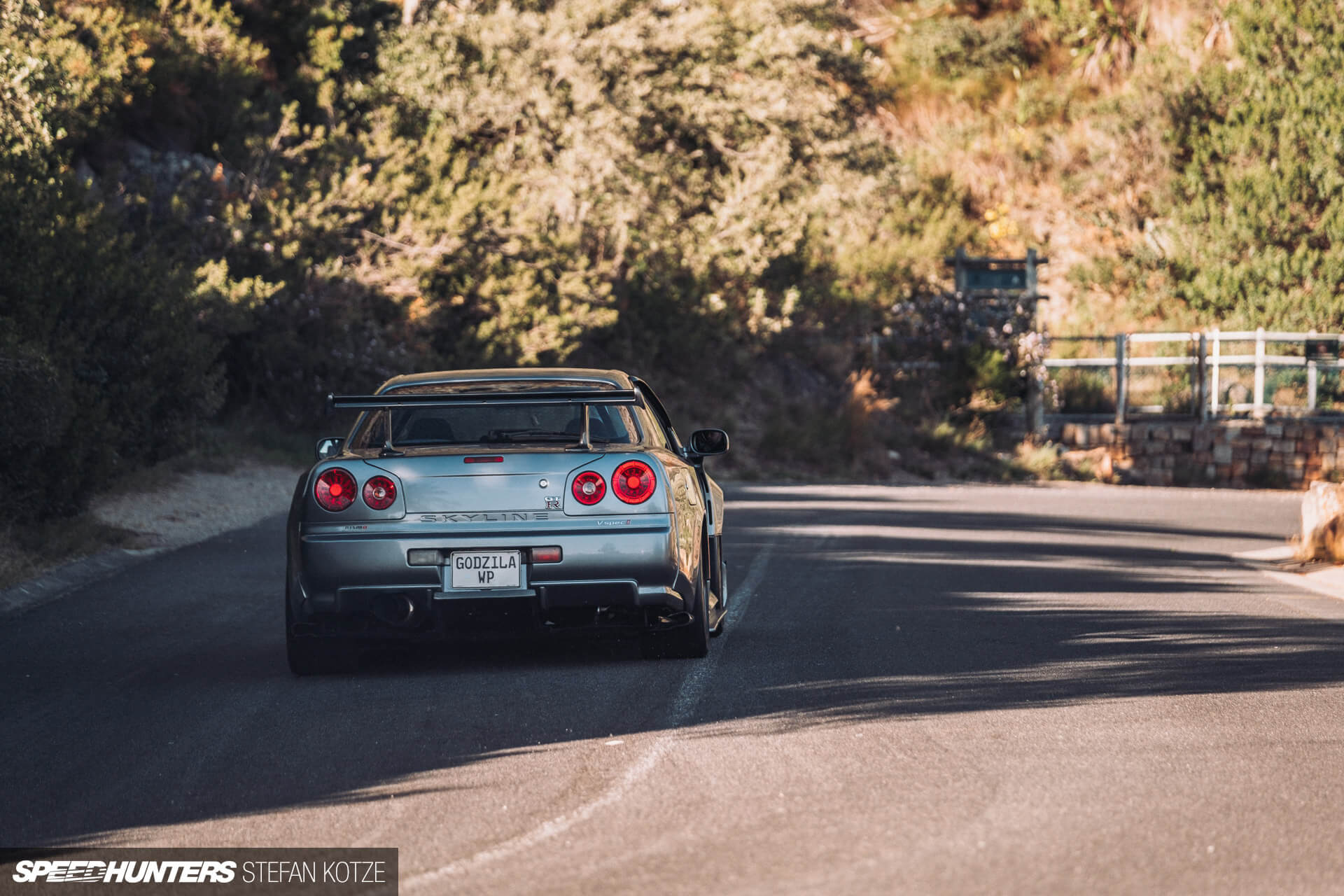 Rear view of the Nissan Skyline R34 GT-R on a 
                    mountain road