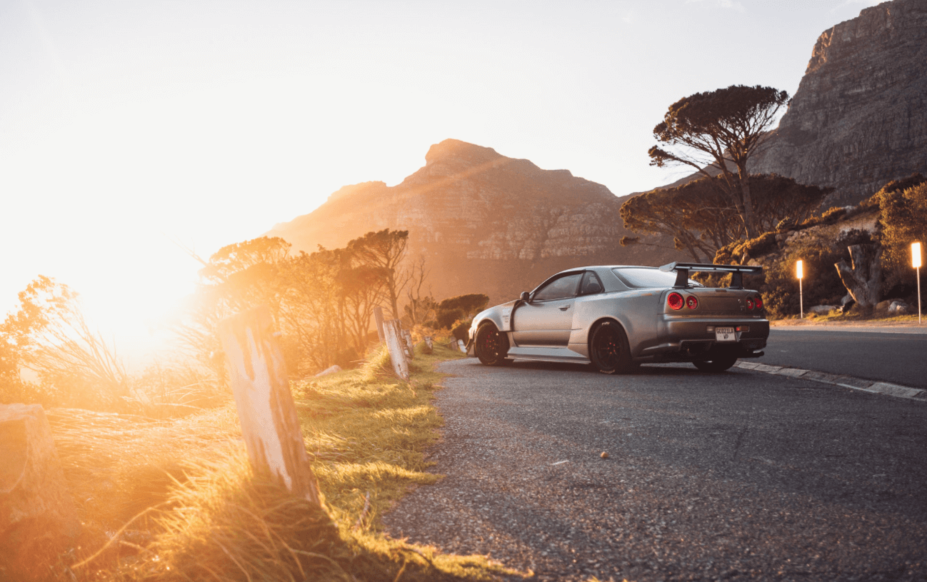 Nissan Skyline R34 GT-R in a mountain 
                    and sunshine background